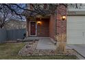 Inviting front entrance with a brick facade, covered porch, and well-maintained lawn at 13096 Birch Dr, Thornton, CO 80241
