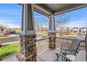 Covered porch with brick columns, chairs, and a view of the street at 3087 Black Canyon Way, Castle Rock, CO 80109