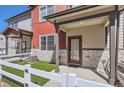 Inviting townhome exterior with a covered porch, stone accents, and manicured artificial lawn at 1353 Reynolds St # 2B, Fort Lupton, CO 80621