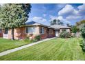 Charming brick home featuring a well-maintained lawn, a quaint walkway, and mature trees, all under a sunny sky at 2028 Perry St, Denver, CO 80212