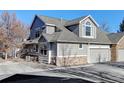 Two-story townhome with gray siding, stone accents, and a double car garage at 6397 Deframe Way, Arvada, CO 80004