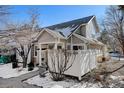 Gray siding townhome with a white fence and snowy landscaping at 6397 Deframe Way, Arvada, CO 80004