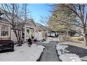 Townhome community with a walkway, snowy landscaping, and mature trees at 6397 Deframe Way, Arvada, CO 80004