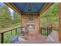 Outdoor living space with stone fireplace, seating, and views of nature at 12653 Rancho Ct, Conifer, CO 80433