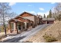 Side view of a house with a garage and stone porch, showcasing the home's architecture and design at 12653 Rancho Ct, Conifer, CO 80433