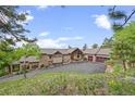 Well-maintained home exterior featuring a driveway, mature trees and attractive landscaping at 12653 Rancho Ct, Conifer, CO 80433
