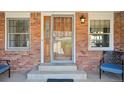 Charming brick porch with a secured wood door, sidelight window and seating, enhancing curb appeal at 9977 Falcon Creek Dr, Highlands Ranch, CO 80130