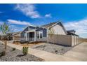 Attractive home featuring a blue and gray exterior, stone accents, manicured front yard and a vinyl fence at 5150 N Quemoy Ct, Aurora, CO 80019