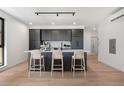 Modern kitchen features dark cabinets, a white countertop island with bar stools, and stainless steel appliances at 1601 Park Ave # 307, Denver, CO 80218