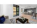 Living room with hardwood floors, large windows, and modern decor with view into the kitchen at 1601 Park Ave # 307, Denver, CO 80218