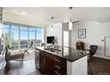 Modern kitchen island with dark countertops and seating, open to a living area with expansive city views at 891 14Th St # 3415, Denver, CO 80202