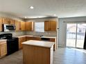 Kitchen featuring ample wood cabinets, a center island, stainless steel appliances, and sliding glass door to the back yard at 10117 Granby St, Commerce City, CO 80022