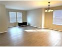 Bright and airy living room with wood-look floors, modern light fixture and plenty of natural light from the large windows at 10117 Granby St, Commerce City, CO 80022