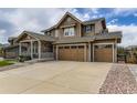 Inviting two-story home with a stone-accented porch and a wide driveway leading to a three-car garage at 15705 Red Deer Dr, Morrison, CO 80465