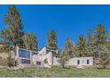 Striking modern home with flat roof design, surrounded by mature pine trees on a lush green lot at 1559 Apex Rd, Franktown, CO 80116