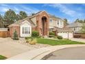 Beautiful two-story home featuring a brick facade, arched entryway, three-car garage, and well-maintained landscaping at 4220 S Yarrow Ct, Lakewood, CO 80235