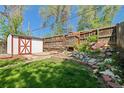 Backyard includes a shed with white door, wooden fence, green grass, and a rock garden at 3024 S Sherman St, Englewood, CO 80113