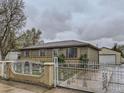 View of home's exterior with a brick and wrought iron fence and detached garage at 5481 Xanadu St, Denver, CO 80239