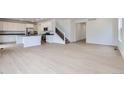 Open-concept living space with hardwood floors, white walls, and a modern kitchen in the background at 28625 E 6Th Pl, Watkins, CO 80137