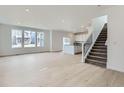 Bright and airy living room featuring hardwood floors, large windows, and access to the kitchen and staircase at 28625 E 6Th Pl, Watkins, CO 80137