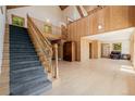 Bright living room with a staircase, wood paneling, hardwood floors, and a vaulted ceiling at 3581 Gap Rd, Golden, CO 80403