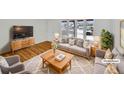 Staged living room boasts abundant natural light with stylish furniture and wood flooring at 11769 Clayton St, Thornton, CO 80233