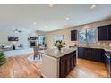 Open-concept kitchen and living space with a granite island, dark cabinets, and hardwood floors at 24288 E Brandt Ave, Aurora, CO 80016