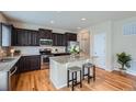 Modern kitchen with dark cabinetry, stainless steel appliances, granite counters, and a center island at 24288 E Brandt Ave, Aurora, CO 80016