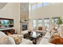 Bright living room with tall ceilings, a stone fireplace, and comfortable seating arrangements at 5737 Amarosa Dr, Parker, CO 80134