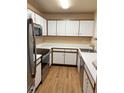 Galley kitchen with white cabinets, stainless steel appliances, and wood-look floors at 5775 W Atlantic Pl # 103, Lakewood, CO 80227