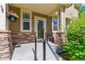Cozy front porch with stone accents, a hanging flower basket, and a charming entrance to the home at 14247 W 84Th Cir # A, Arvada, CO 80005