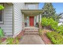 Inviting entryway with a red front door, brick accents, and decorative chairs at 8807 Tuscany Ln, Highlands Ranch, CO 80130