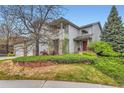 This charming home with a red front door is surrounded by beautiful landscaping and mature trees at 8807 Tuscany Ln, Highlands Ranch, CO 80130