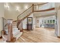Elegant foyer with a curved staircase, hardwood floors, and views into the living spaces at 9121 Sunshine Meadow Pl, Parker, CO 80134