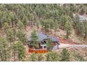 Aerial view of a home nestled in a lush forest with an outdoor entertaining area and ample parking at 795 Pine Brook Rd, Boulder, CO 80304