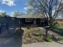 View of the front yard featuring an overgrown garden, containers, and a large dumpster at 1985 Blackhawk St, Aurora, CO 80011