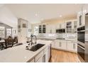 Bright kitchen featuring white cabinets, stainless steel appliances, quartz countertops, and hardwood floors at 7360 S Owens Ct, Littleton, CO 80127