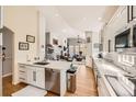 Bright kitchen featuring white cabinets, stainless steel appliances, quartz countertops, hardwood floors, and open-concept layout at 7360 S Owens Ct, Littleton, CO 80127