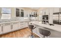 Bright kitchen featuring white cabinets, stainless steel appliances, quartz countertops, and hardwood floors at 7360 S Owens Ct, Littleton, CO 80127