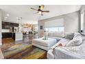 Open-concept living room with a ceiling fan, large windows, hardwood floors, and a modern, neutral-toned sectional sofa at 18083 Telford Ave, Parker, CO 80134