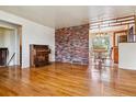 Open-concept living room showcasing beautiful hardwood floors, a brick accent wall, and seamless access to the dining area at 541 Yucca Hills Rd, Castle Rock, CO 80109
