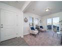 Bright living room with carpet, white walls, two chairs, windows, and sliding glass door at 46505 Avery Ln, Commerce City, CO 80022