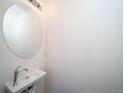 A well-lit powder room featuring a modern round mirror and wall-mounted sink at 46505 Avery Ln, Commerce City, CO 80022