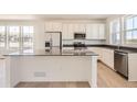 Bright kitchen featuring white cabinetry, stainless steel appliances, a large center island, and plenty of natural light at 6562 Arbor Blvd # 1, Thornton, CO 80602