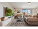 Bright living room featuring a comfortable gray couch, area rug, and a large screen TV on display at 480 S Marion Pkwy # 1002, Denver, CO 80209