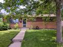 Inviting brick home featuring a lush green lawn and a tidy walkway to the entrance at 1500 S Perry St, Denver, CO 80219