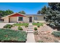 Inviting single-story home with vibrant landscaping, concrete walkway, and a classic neutral exterior at 5067 S Mabre Ct, Littleton, CO 80123