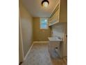 A practical laundry room features a utility sink, shelving, and a window for natural light at 1364 Iola St, Aurora, CO 80010