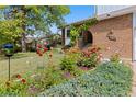 Landscaped front yard with colorful flowers and lush greenery leading to the brick facade home with an arched entryway at 3907 E 133Rd Ct, Thornton, CO 80241