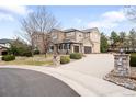 Spacious driveway leading to a three-car garage, complemented by lush landscaping and a basketball hoop at 8390 Coyote Dr, Castle Pines, CO 80108